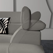 Graues Ecksofa mit verstellbarer Kopfstütze, seitliche Perspektive, dekoratives Kissen mit schwarz-weißem Muster.