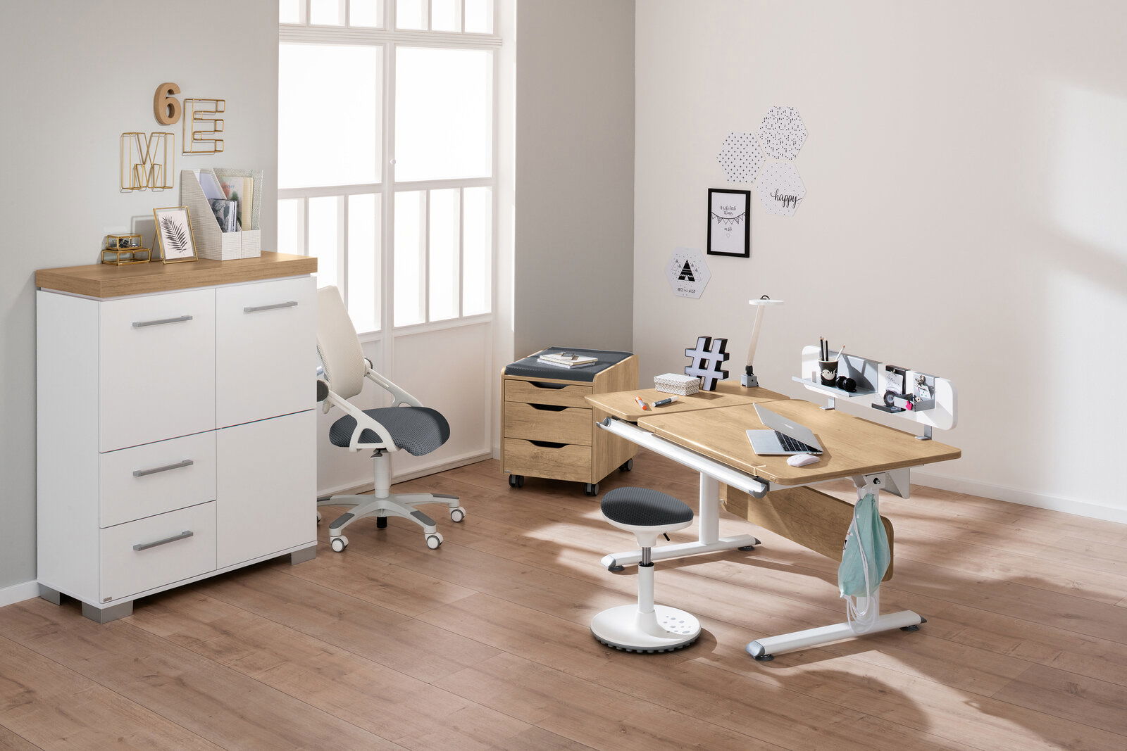 Moderner Schreibtisch in einem hellen Raum, mit ergonomischem Stuhl und Stauraum, aus seitlicher Perspektive fotografiert.