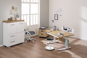 Moderner Schreibtisch in einem hellen Raum, mit ergonomischem Stuhl und Stauraum, aus seitlicher Perspektive fotografiert.