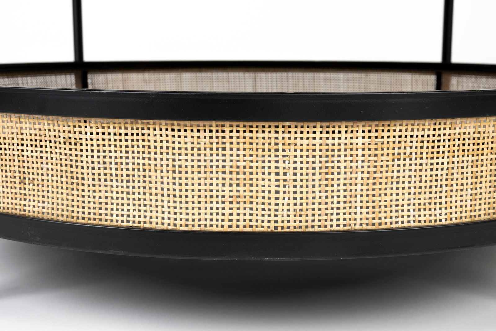 Nahaufnahme eines Couchtischs mit schwarzem Rahmen und geflochtenem Rattan-Design, seitliche Perspektive.