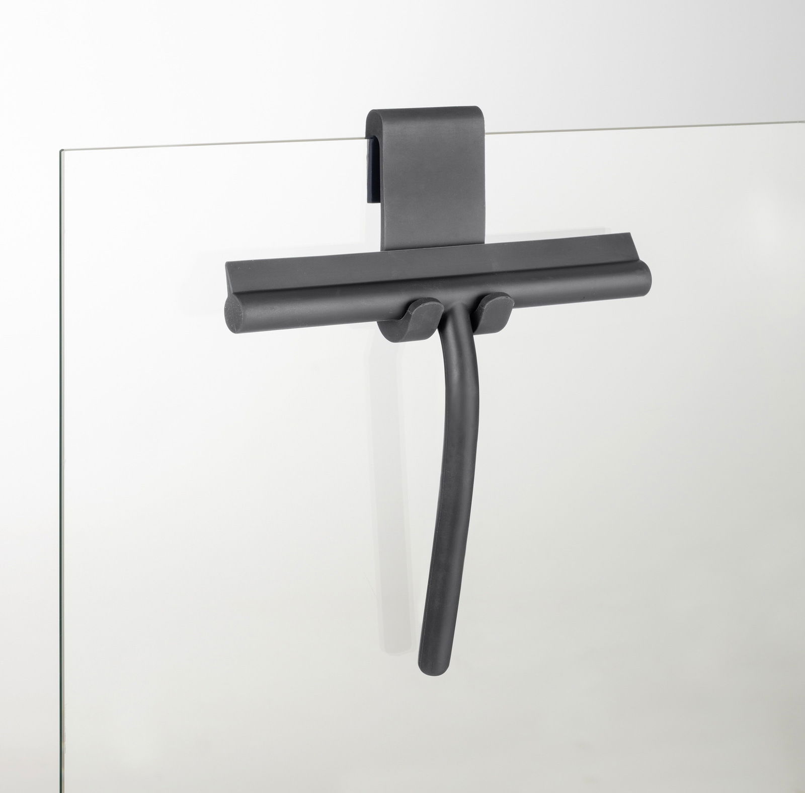 Moderner Badezimmerwischer aus Silikon in dunkler Farbe, an einer Glaswand hängend, seitliche Perspektive.