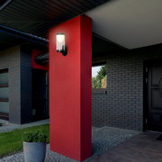 Moderne Akku-Außenwandleuchte an einer roten Wand, seitliche Perspektive