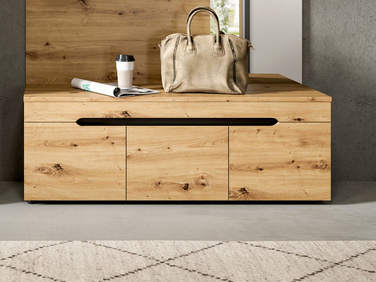 Frontale Ansicht einer modernen Holzkommode aus hellem Massivholz mit drei Türen und schwarzer Griffmulde, dekoriert mit Tasche, Coffee-to-go-Becher und Zeitschrift auf der Oberfläche.