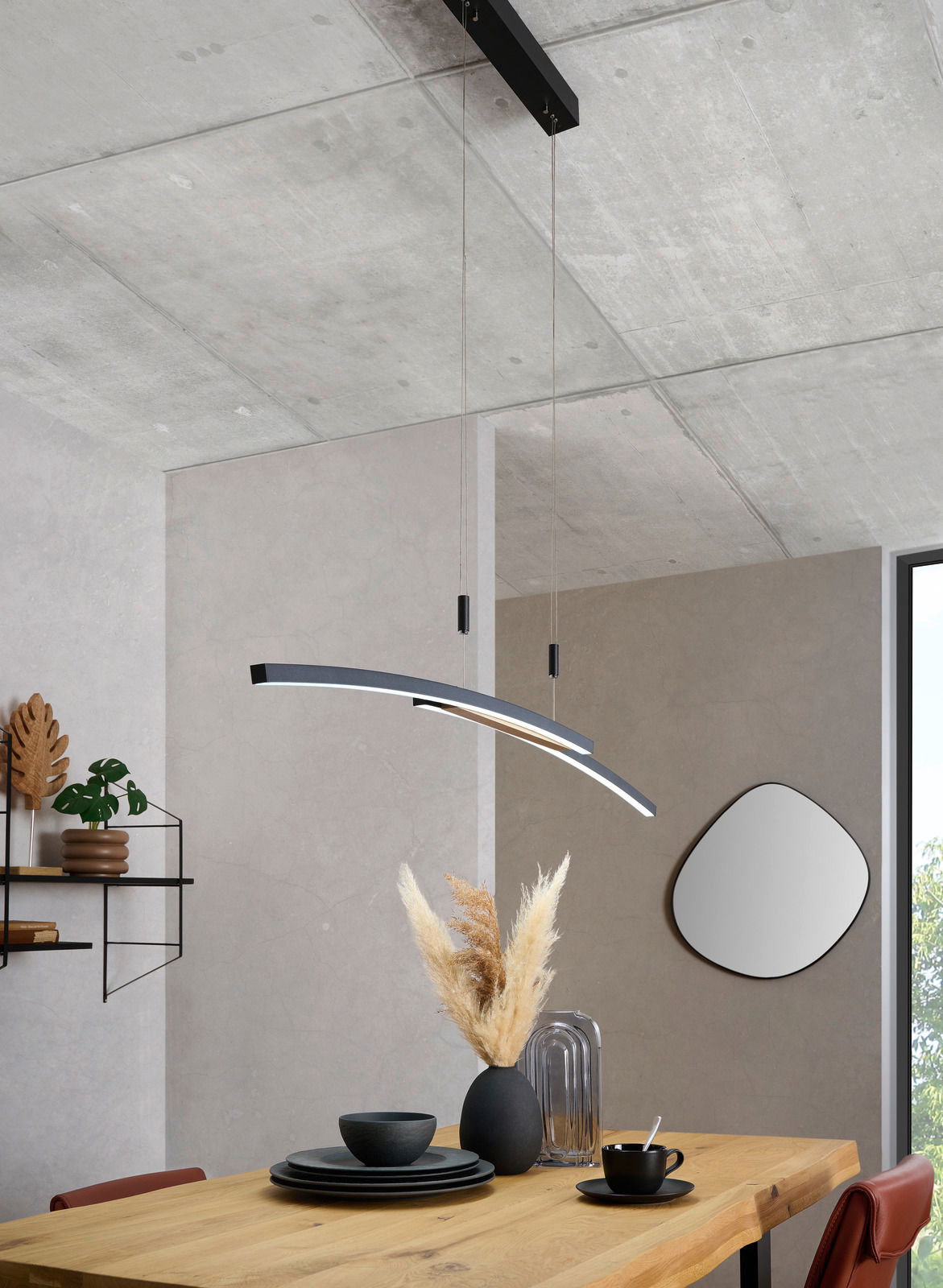 Moderne LED-Hängeleuchte in geschwungenem Design über einem Esstisch, seitliche Perspektive.