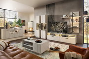 Moderne Wohnzimmer-Wandkombination in heller Farbe mit TV-Schrank, Regalen und Vitrinen, seitliche Perspektive.
