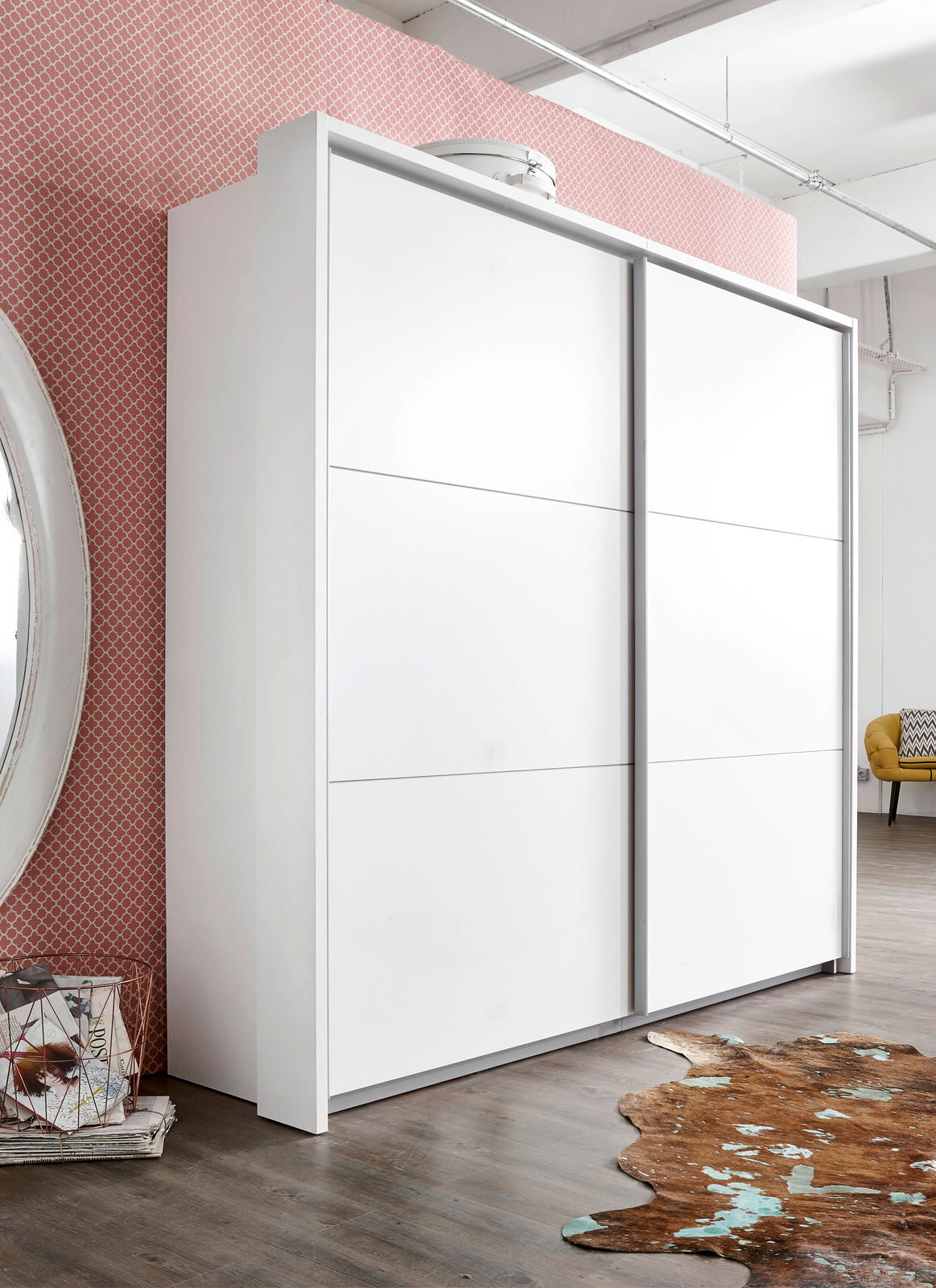 Moderner weißer Schwebetürenschrank mit zwei Türen, seitliche Perspektive, vor einer gemusterten Wand und auf einem Holzboden stehend.