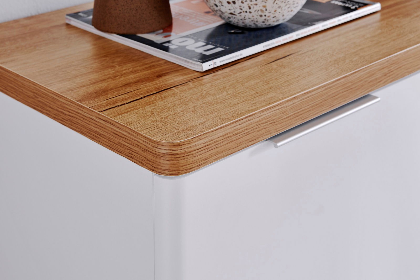 Nahaufnahme eines Sideboards mit einer Holzoberfläche und einer weißen Front, von oben betrachtet.
