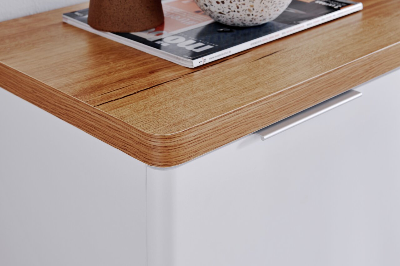 Nahaufnahme eines Sideboards mit einer Holzoberfläche und einer weißen Front, von oben betrachtet.