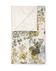 Tagesdecke mit floralem Muster in Gelb- und Grüntönen, teilweise umgeschlagen, aus der Vogelperspektive fotografiert.