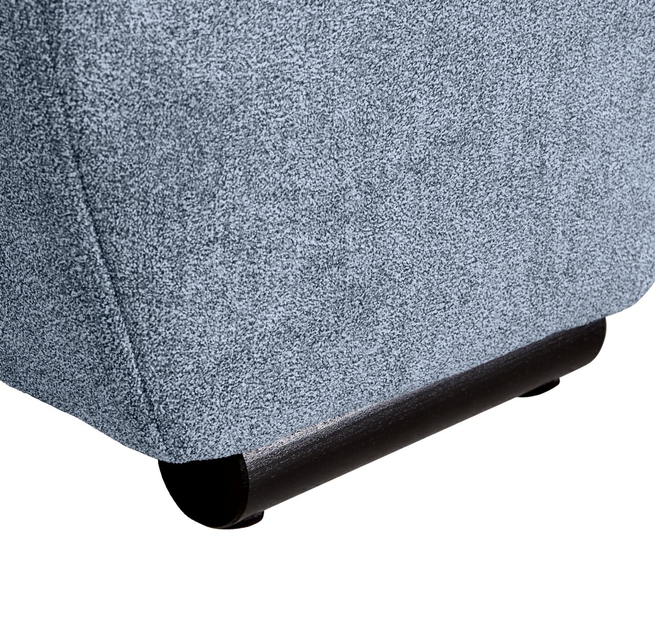 Nahaufnahme der unteren Ecke eines Big-Sofas mit grauem Stoffbezug und dunklem Holzfuß, seitliche Perspektive.