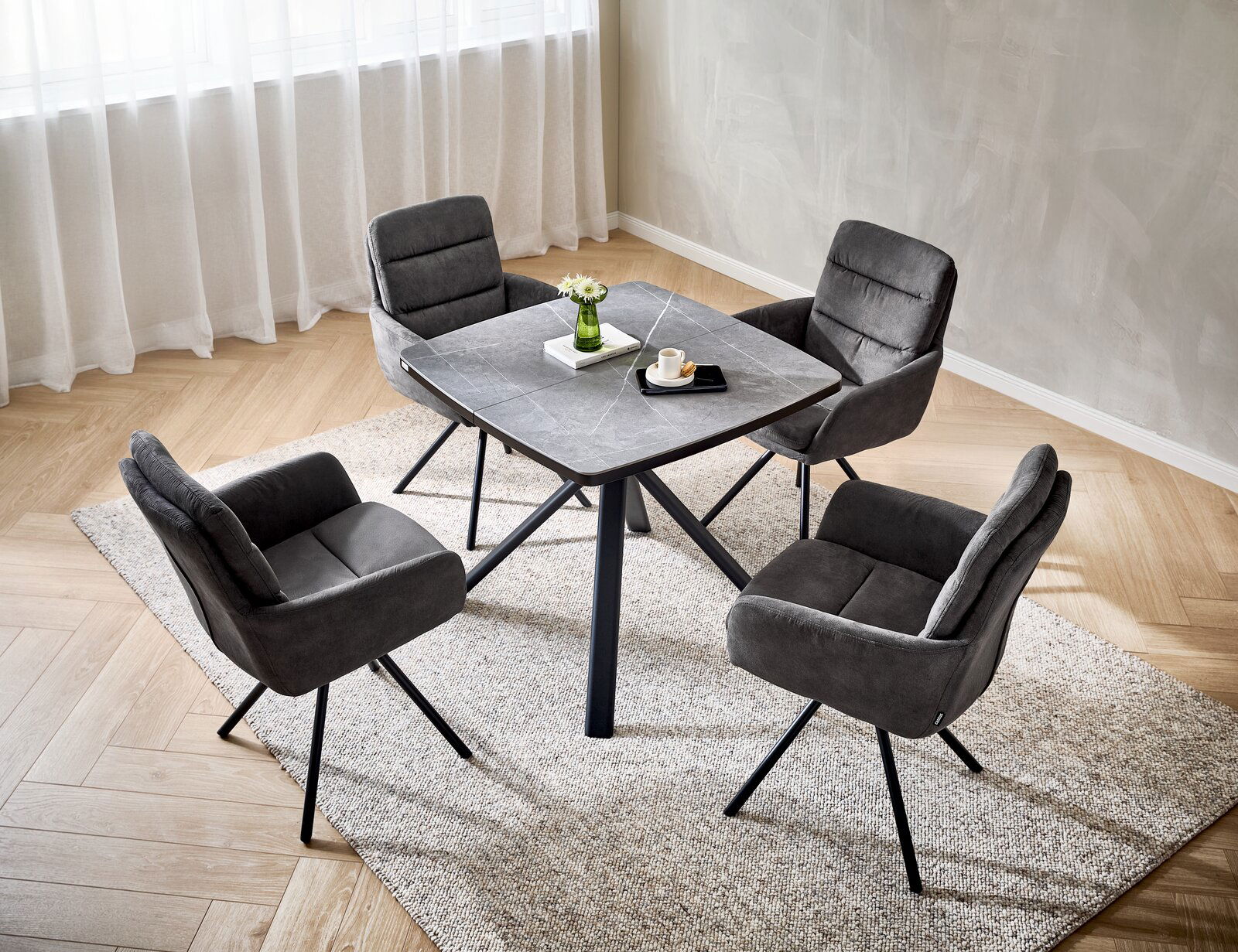 Cantus Armlehnstuhl SCOTTY 2.0 Vier graue Armlehnstühle um einen quadratischen Tisch in einem modernen Esszimmer, aus der Vogelperspektive fotografiert.