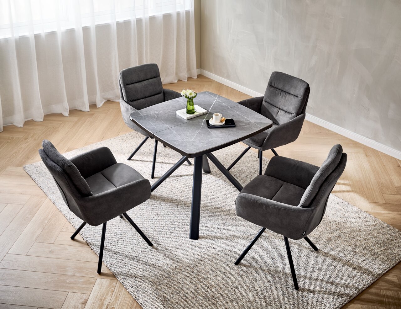 Cantus Armlehnstuhl SCOTTY 2.0 Vier graue Armlehnstühle um einen quadratischen Tisch in einem modernen Esszimmer, aus der Vogelperspektive fotografiert.