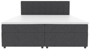 Dunkelgraues Boxspringbett mit gepolstertem, quadratisch gestepptem Kopfteil und weißer Matratzenauflage, Frontalansicht.