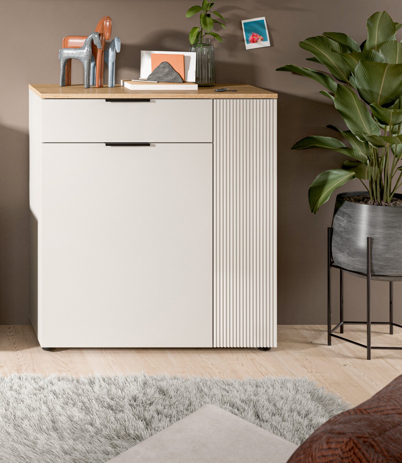 Moderne Kommode mit Holzplatte, dekoriert mit Skulpturen und Pflanzen, aus frontaler Perspektive.