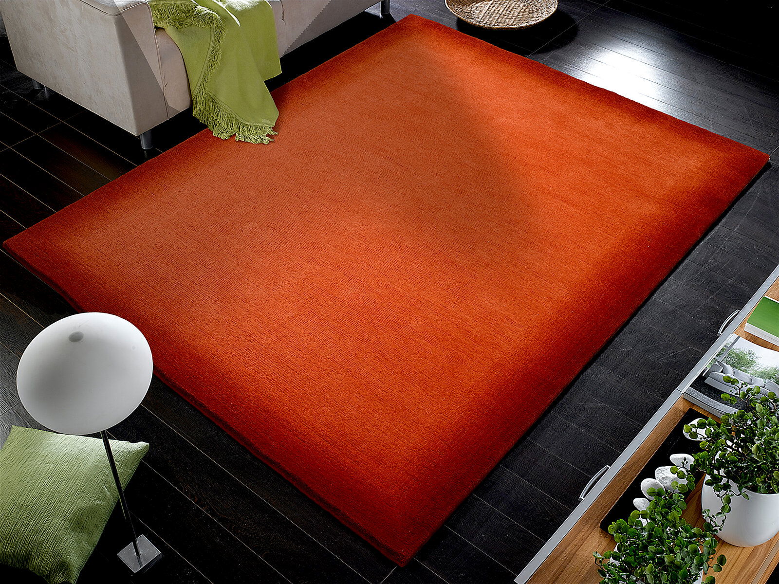 OCI Wollteppich VINCIANO Roter Wollteppich in einem modernen Wohnzimmer, von oben betrachtet, mit dunklem Holzboden und grünen Akzenten.