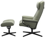 Seitliche Ansicht eines grünen Einzelsessels mit passendem Hocker, beide mit schwarzem Drehfuß.