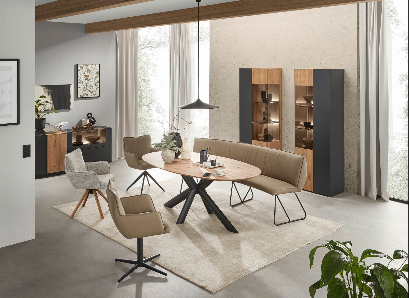 Moderner Essbereich mit ovalem Esstisch aus Holz und Metallgestell, umgeben von beigen Stühlen und einer Sitzbank, seitliche Perspektive.