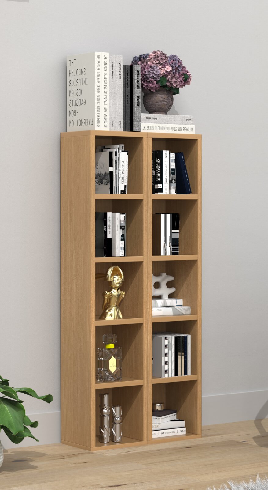 Modernes, schmales Bücherregal aus hellem Holz mit mehreren offenen Fächern, gefüllt mit Büchern und Deko; oben liegen große Bildbände und eine Vase mit violetten Hortensien, fotografiert in frontaler Perspektive leicht von links in einem hellen Wohnraum.
