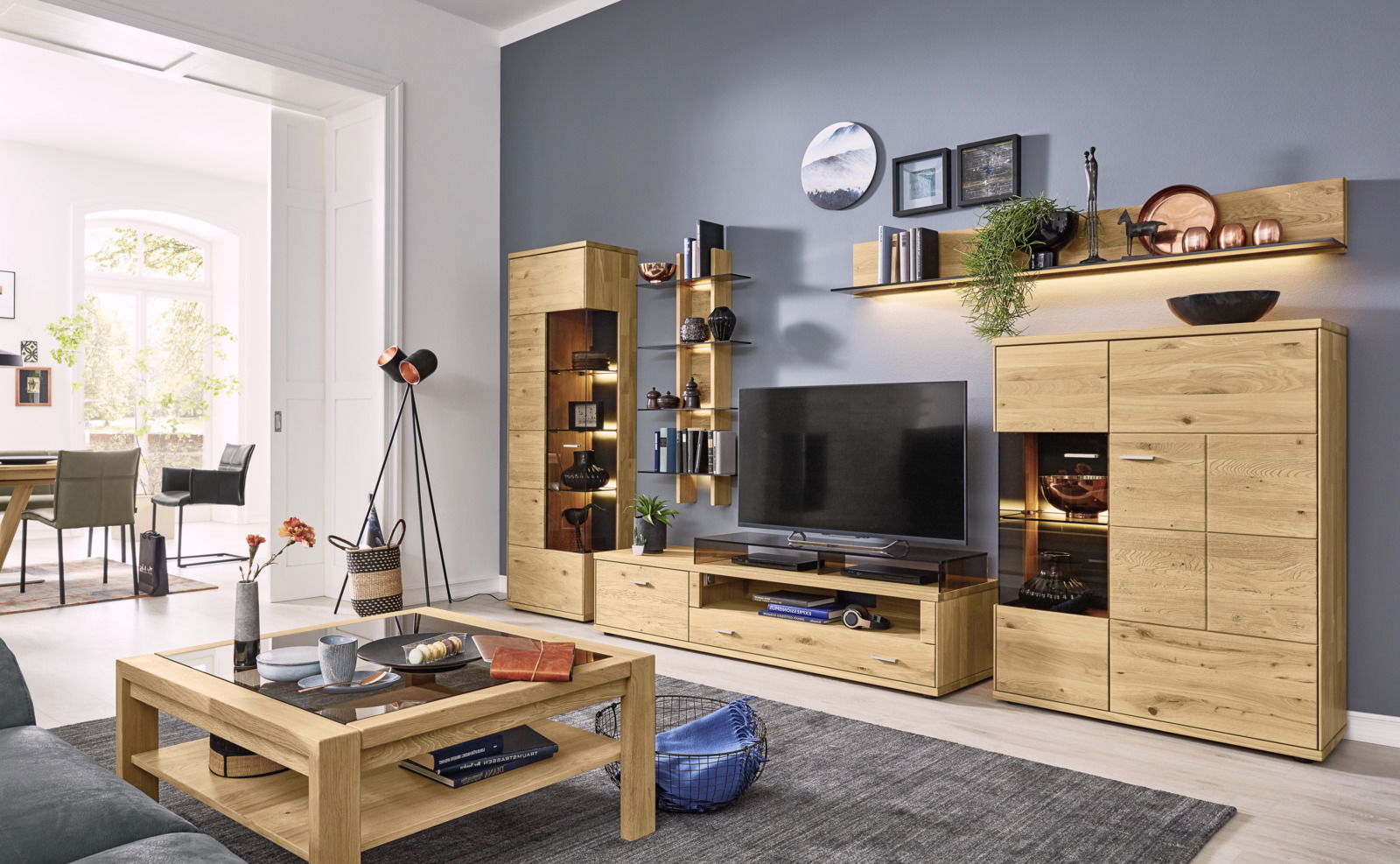Moderne Wohnzimmer-Wandkombination aus Holz mit TV-Schrank, Regalen und dekorativen Elementen, seitliche Perspektive.