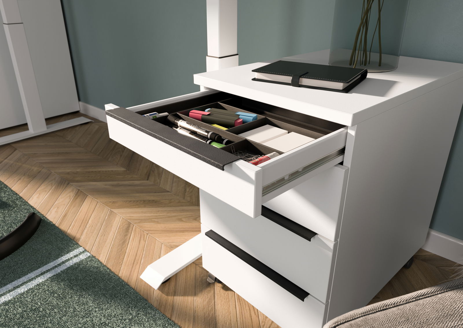 Weißer Rollcontainer mit geöffnetem Schubfach, gefüllt mit Büroartikeln, aus seitlicher Perspektive fotografiert.