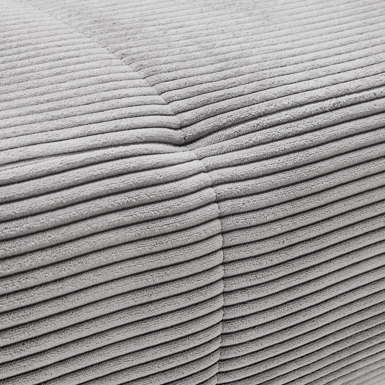 Nahaufnahme einer grauen, gerippten Stoffoberfläche eines Ecksofas aus der Perspektive von oben.