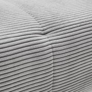 Nahaufnahme einer grauen, gerippten Stoffoberfläche eines Ecksofas aus der Perspektive von oben.