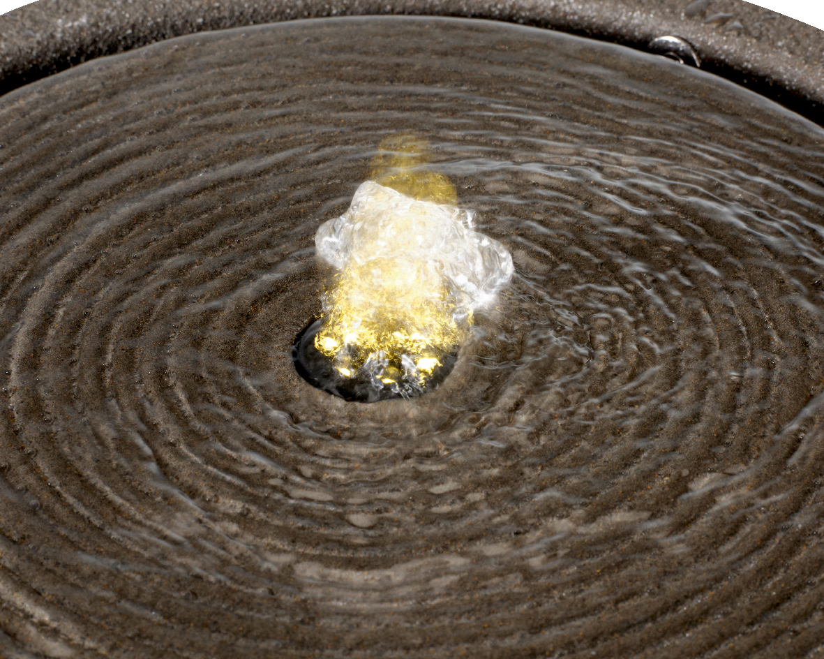 Nahaufnahme eines Brunnens aus recyceltem Kunststoff mit sprudelndem Wasser in der Mitte, von oben betrachtet.