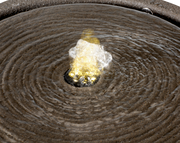 Nahaufnahme eines Brunnens aus recyceltem Kunststoff mit sprudelndem Wasser in der Mitte, von oben betrachtet.