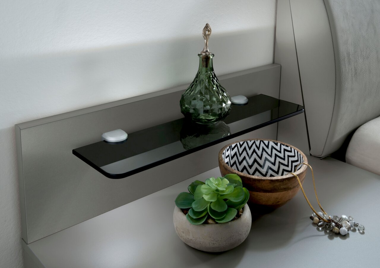 Nachtkonsolen Paneel mit Glasablage, dekoriert mit einer grünen Glasflasche, einer Schale mit Zickzackmuster und einem kleinen Pflanzentopf, seitliche Perspektive