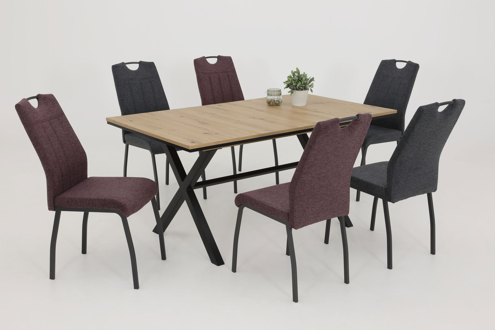 Essgruppe mit einem rechteckigen Holztisch und sechs Stühlen in verschiedenen Farben, aus seitlicher Perspektive fotografiert.