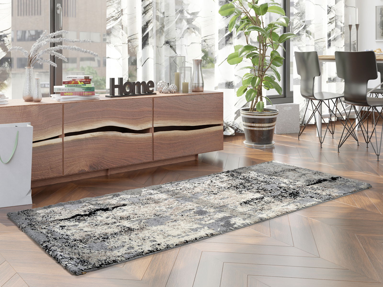 Moderner Designer Teppich in Grau- und Beigetönen auf einem Holzboden, umgeben von stilvollen Möbeln und Pflanzen, aus seitlicher Perspektive fotografiert.