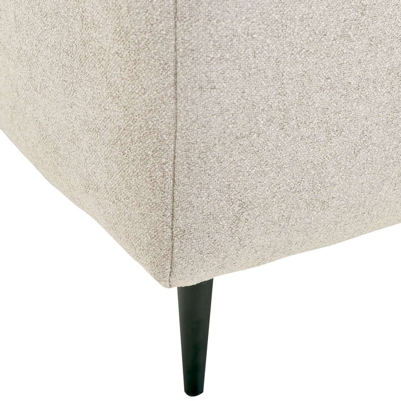 Nahaufnahme der Ecke eines beigen Funktionssofas mit schwarzem, schlankem Bein.