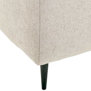 Close-up van de hoek van een beige functionele bank met een slanke zwarte poot.