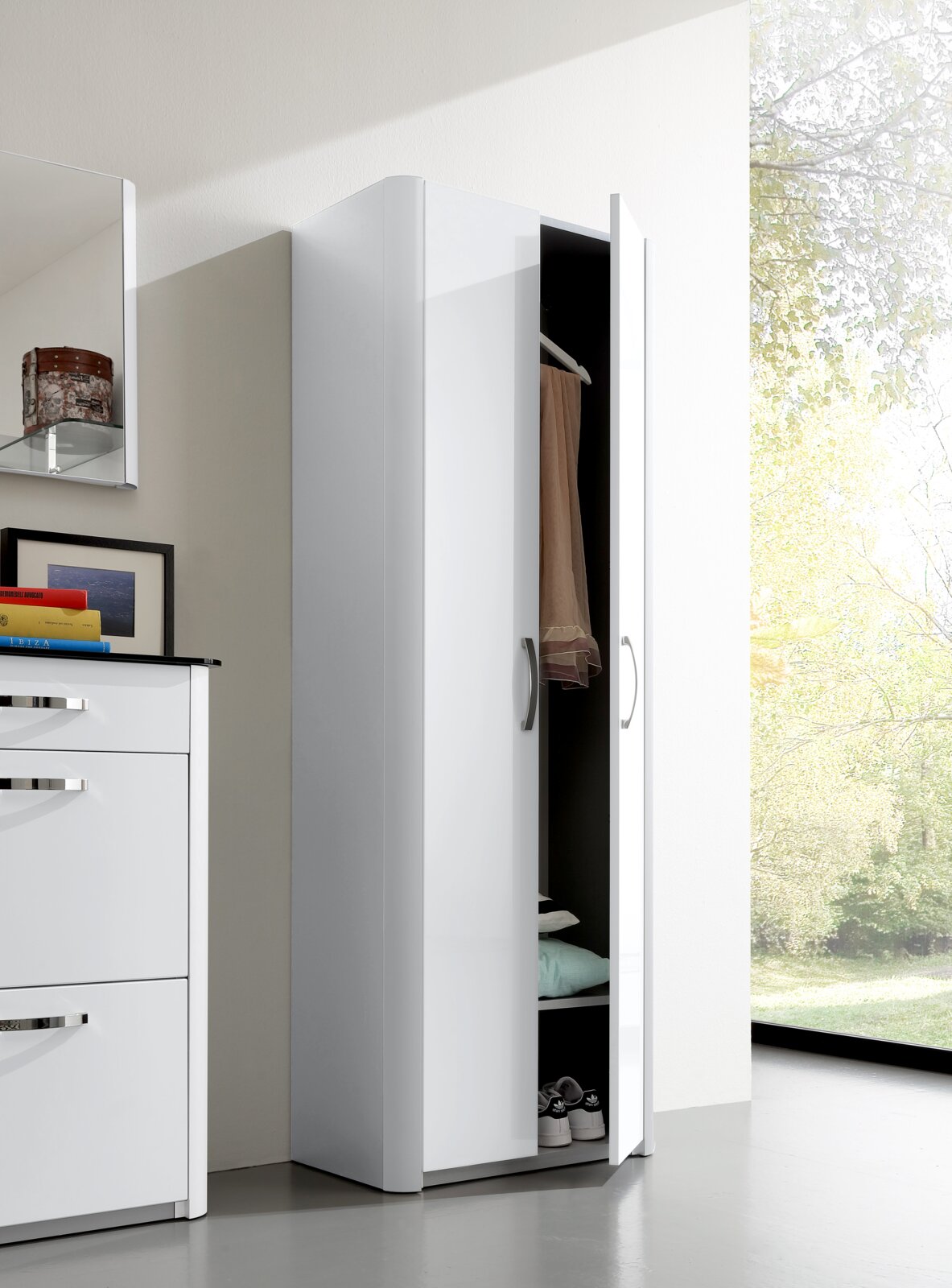 Weißer Mehrzweckschrank mit teilweise geöffneter Tür, zeigt Innenraum mit Kleiderstange und Regalböden, seitliche Perspektive
