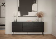 Modernes schwarzes Sideboard mit minimalistischen Linien, dekoriert mit Kerzen und Vasen, vor einem großen abstrakten Kunstwerk an der Wand. Frontalansicht.
