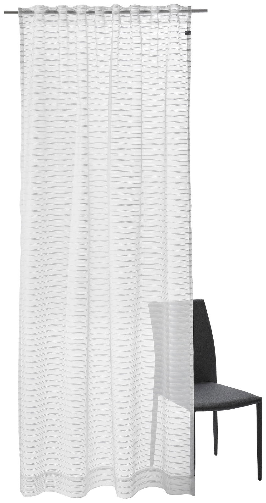 Weißer Dekoschal mit feinen horizontalen Linien, aufgehängt an einer Gardinenstange, mit einem Stuhl im Hintergrund. Frontalansicht.