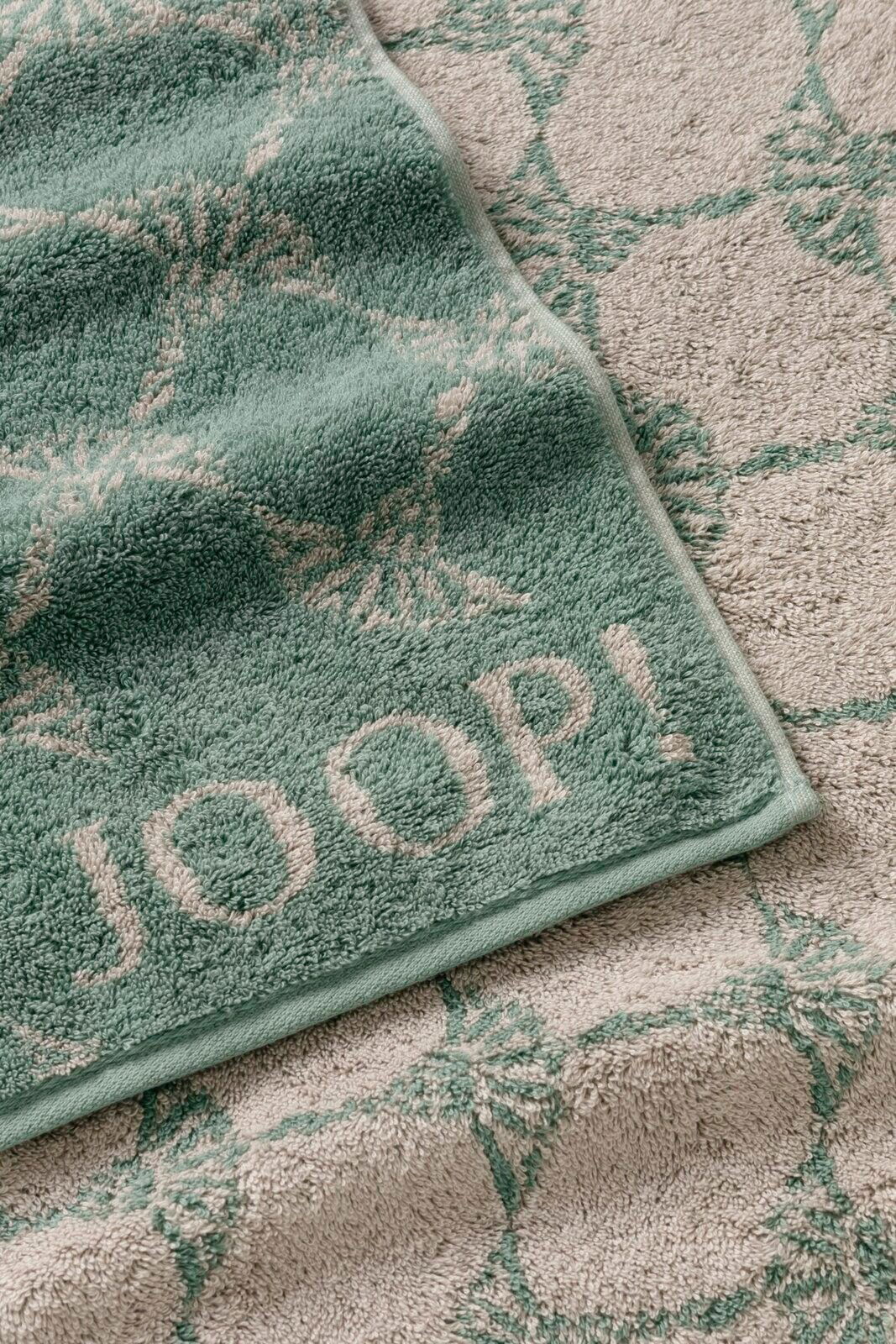 Grünes Handtuch mit geometrischem Muster und dem Schriftzug 'JOOP!' in Nahaufnahme.