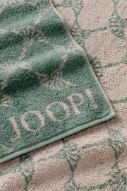 Grünes Handtuch mit geometrischem Muster und dem Schriftzug 'JOOP!' in Nahaufnahme.