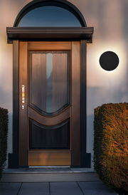 Moderne LED-Außenwandleuchte an einer Hauswand neben einer eleganten Holztür, seitliche Perspektive.