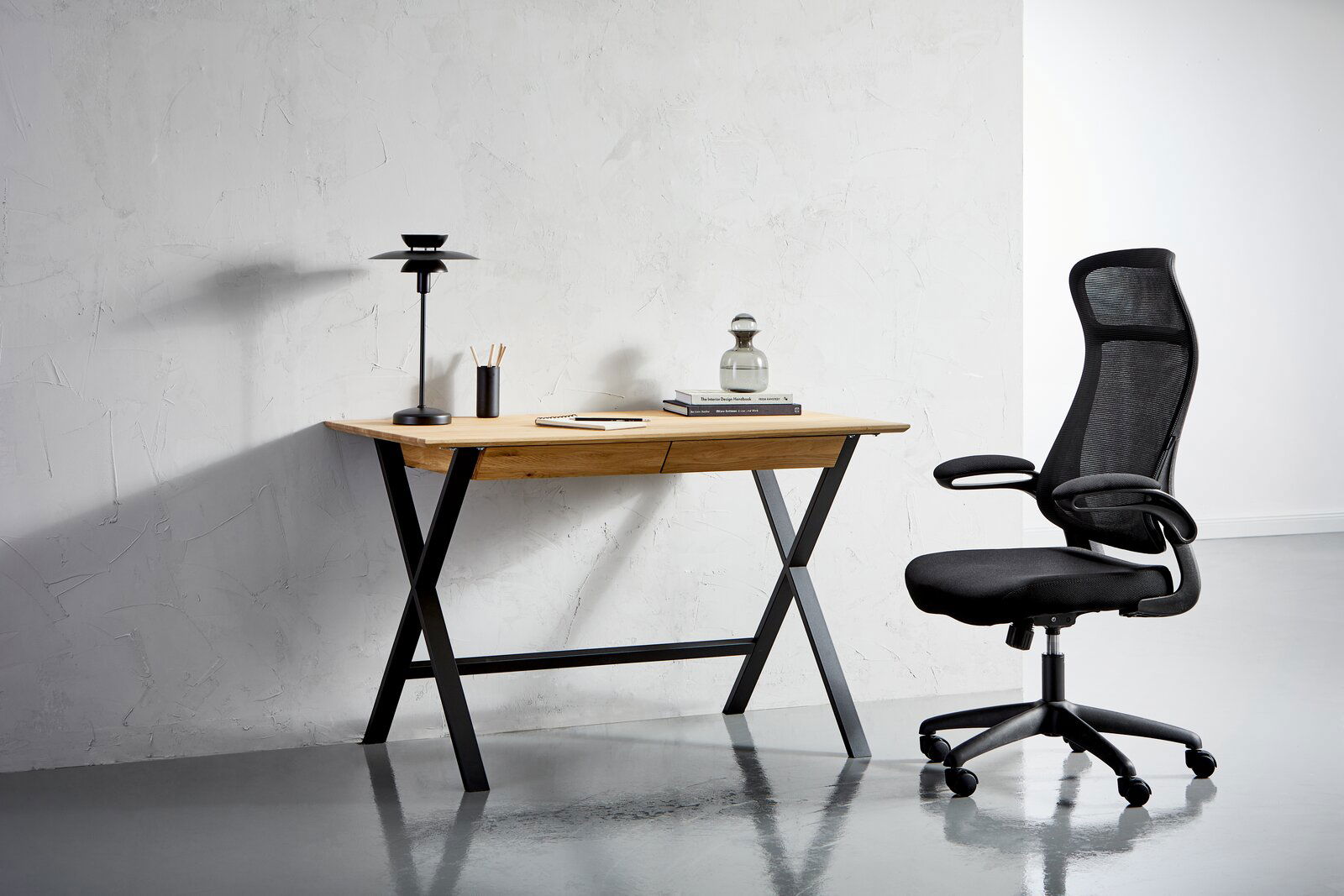 Linea Natura Schreibtisch BERN Moderner Schreibtisch mit Holzplatte und schwarzen Metallbeinen, seitliche Perspektive, mit Bürostuhl und Schreibtischlampe.