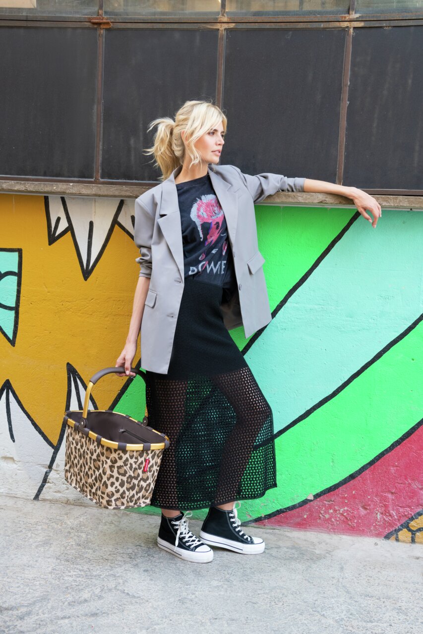 Frau in urbaner Umgebung mit einem Carrybag Frame Leo Macchiato in der Hand, seitliche Perspektive