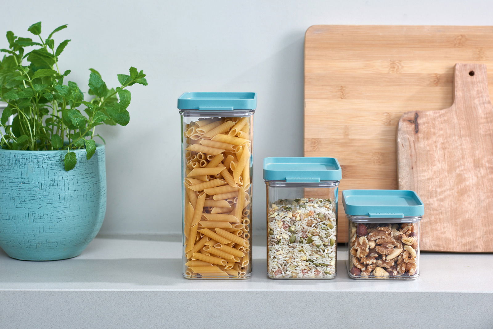 Mepal Vorratsdosen-Set 3-tlg. OMNIA Drei Vorratsdosen Omnia in verschiedenen Größen mit blauen Deckeln, gefüllt mit Nudeln, Körnern und Nüssen, auf einer Küchenarbeitsplatte. Perspektive von vorne.