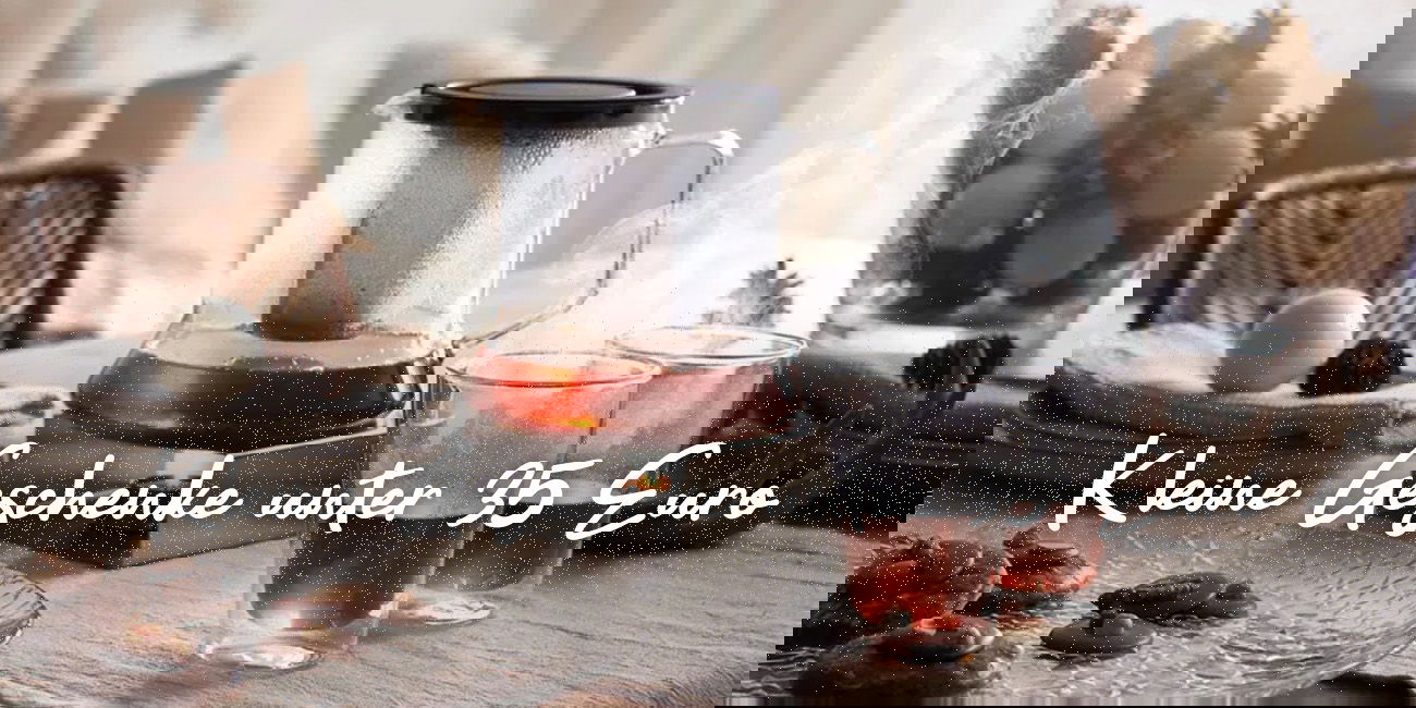 Teekanne mit zwei Gläsern auf winterlich dekoriertem Tisch, darüber Schriftzug „Kleine Geschenke unter 35 Euro“.