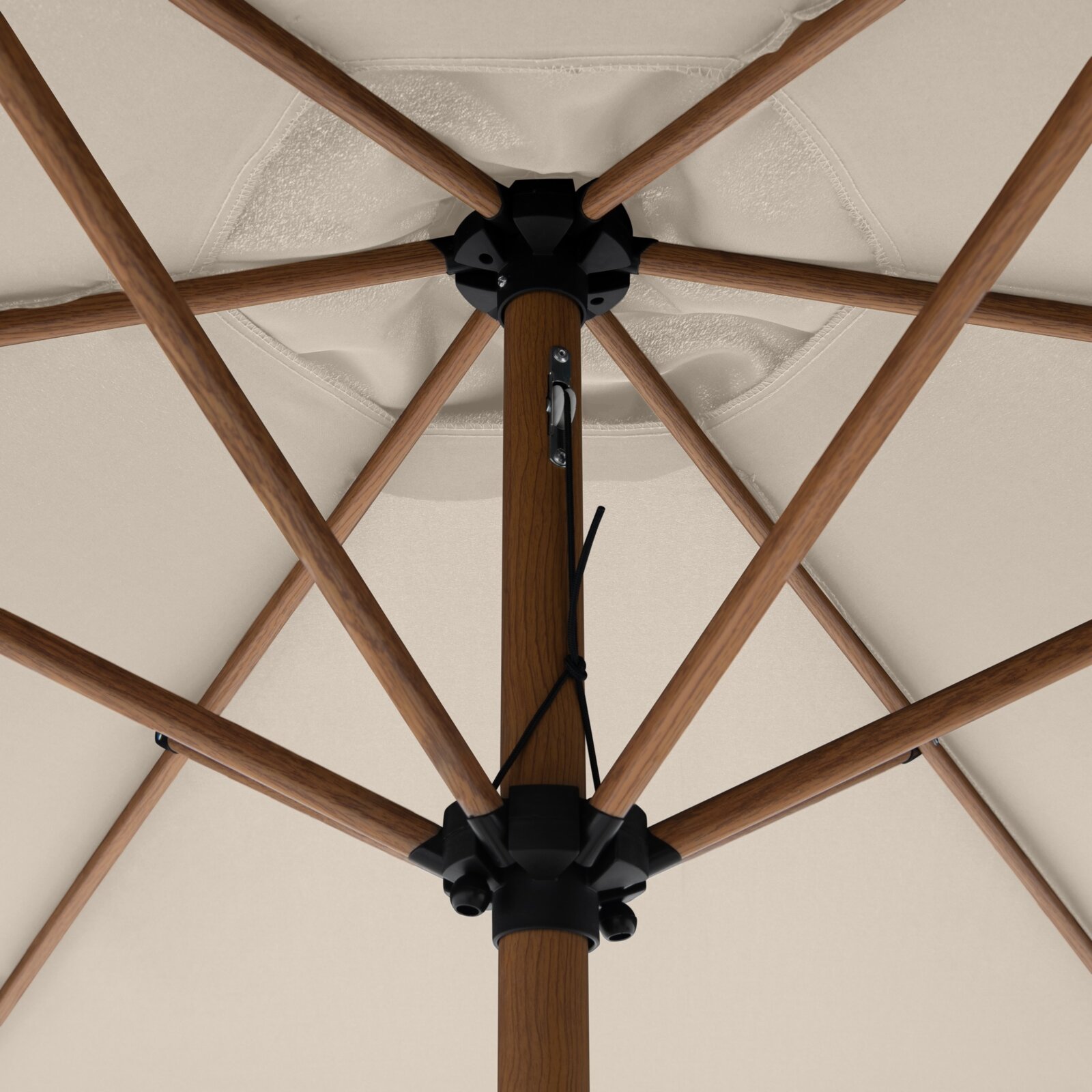 Onderaanzicht van een beige parasol met houten spanten en een centrale houten mast; de zwarte naaf en het kabelmechanisme zijn zichtbaar