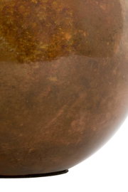 Detailopname van opzij van een afgerond, bruin gepatineerd metalen object met een warme, gevlamde oppervlaktestructuur.