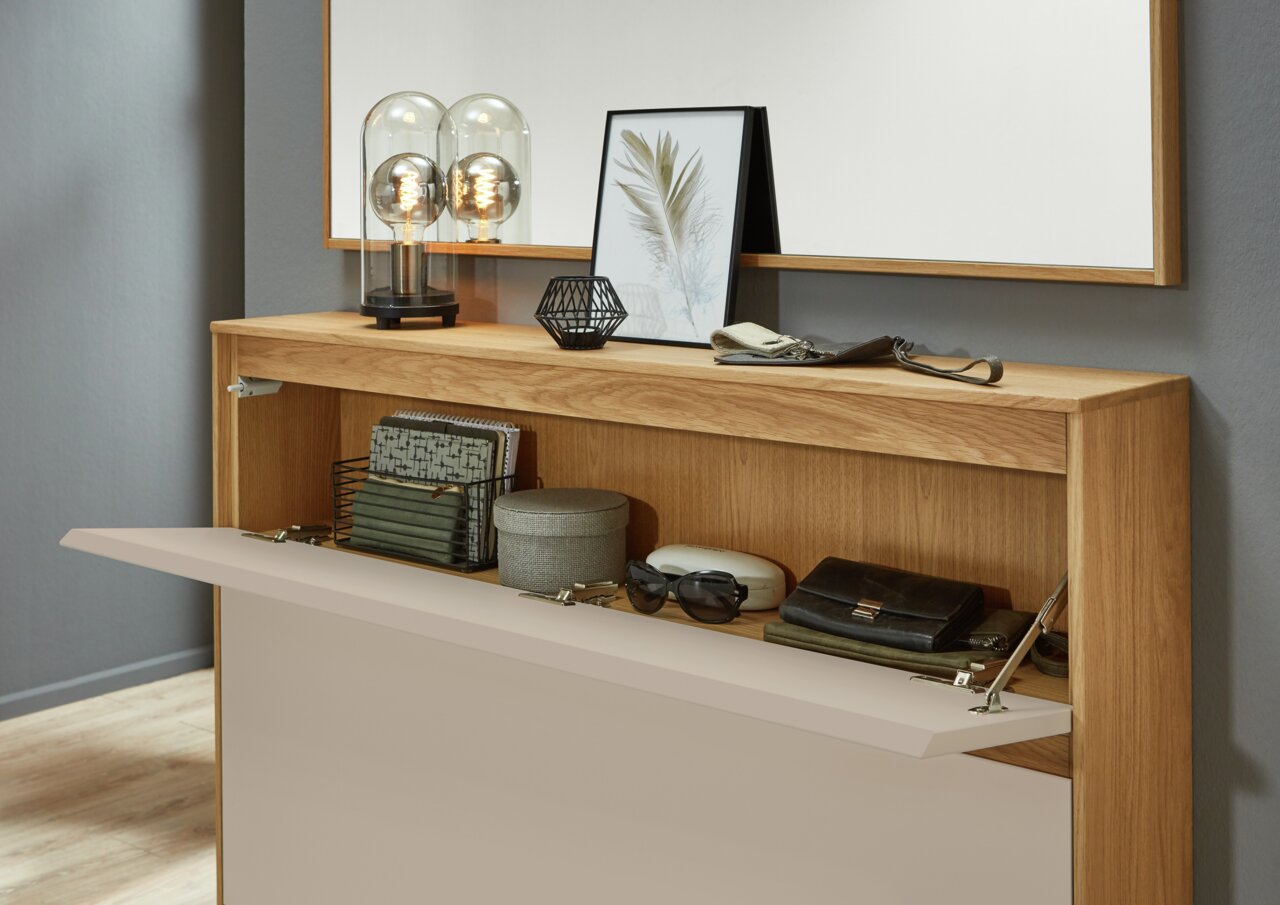 Moderner Schuhschrank aus Holz mit offener Klappe, dekoriert mit Lampen und Bildern, aus der Frontalperspektive.