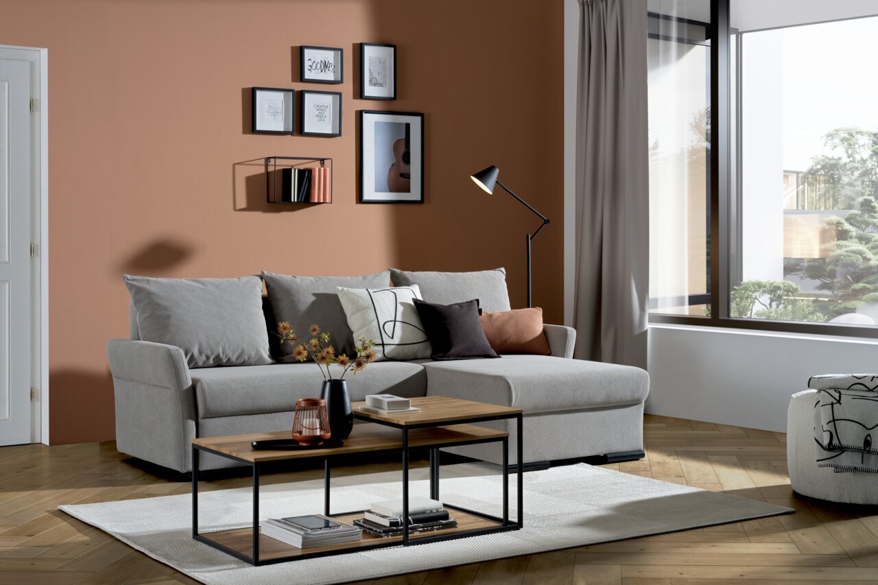 Graue Rundecke (L) in einem modernen Wohnzimmer mit Holzboden, dekoriert mit Kissen und einem Couchtisch, seitliche Perspektive.