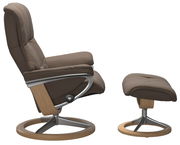 Bequemer Einzelsessel mit Hocker in Seitenansicht, braunes Polster und Holz-Metall-Gestell.