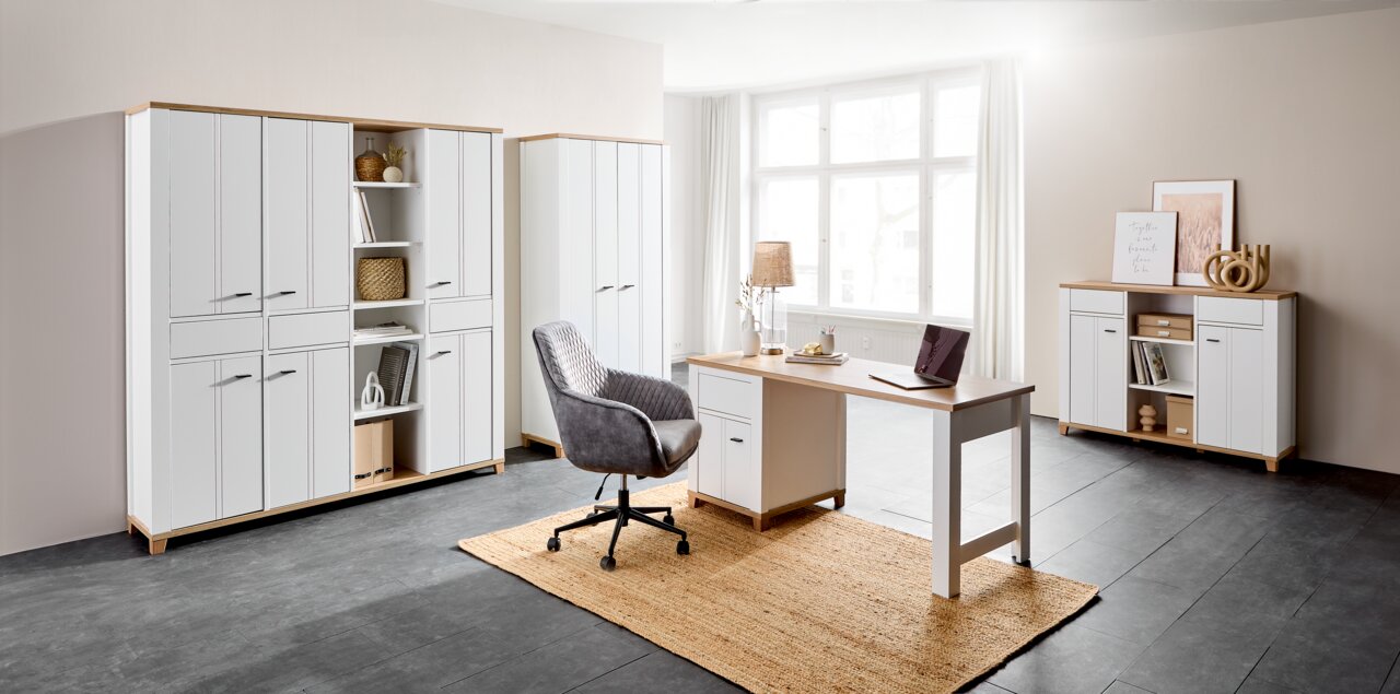 Moderne Büromöbelkombination in heller Umgebung mit Schreibtisch, Drehstuhl und mehreren Schränken, seitliche Perspektive.