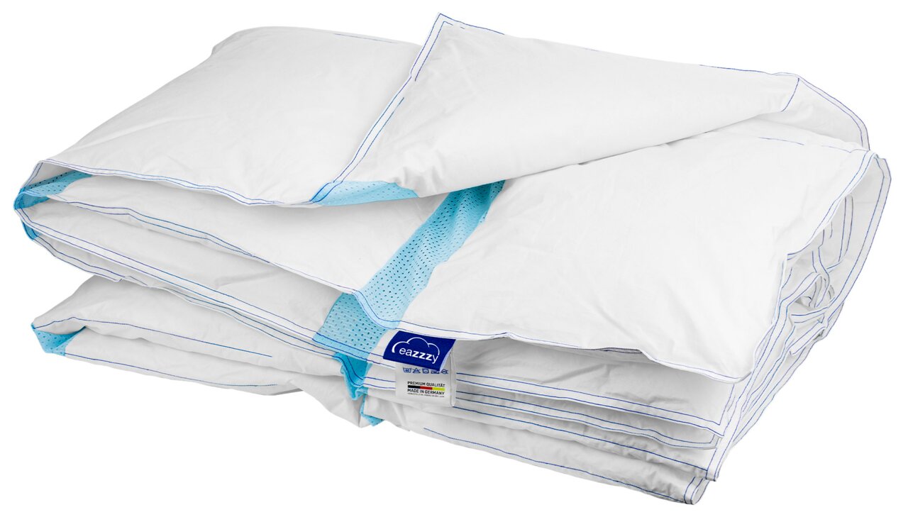 Zusammengefaltete weiße Bettdecke mit blauen Nähten und türkisfarbenem Mesh-Einsatz, schräg von vorne in leichter Draufsicht fotografiert.